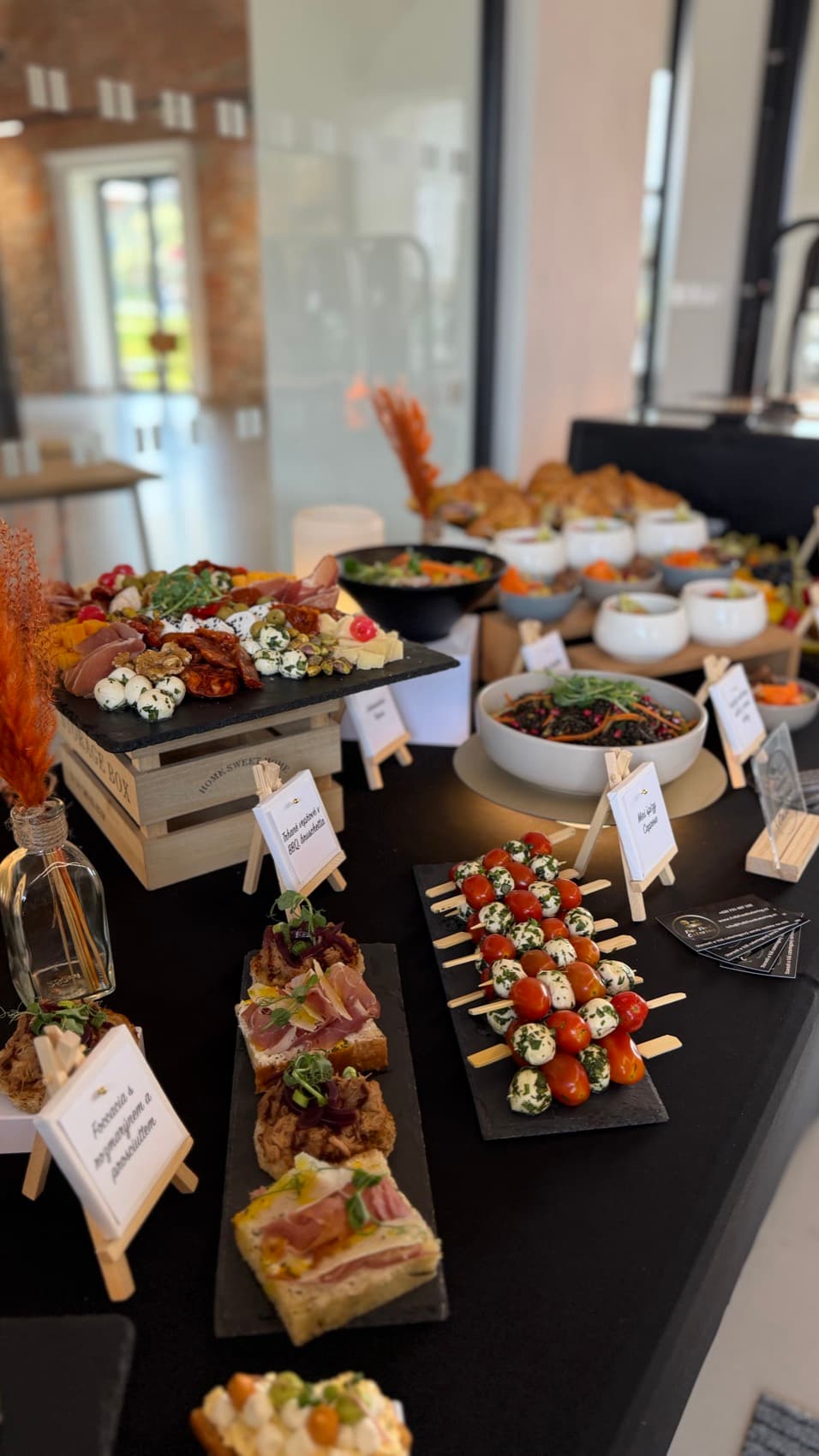 Rautové stojany s finger food v sále s cihlovou zdí